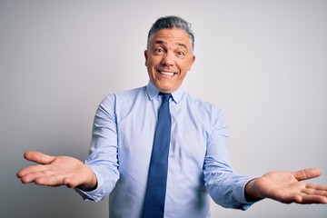 Middle age handsome grey-haired business man wearing elegant shirt and tie smiling cheerful with open arms as friendly welcome, positive and confident greetings