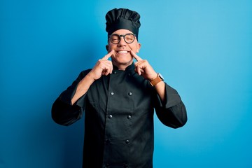 Middle age handsome grey-haired chef man wearing cooker uniform and hat Smiling with open mouth, fingers pointing and forcing cheerful smile