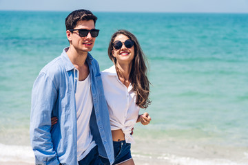 Vacation romantic lovers young happy couple holding hands walking on sand by sea having fun and relaxing together on tropical beach.Summer vacations and travel