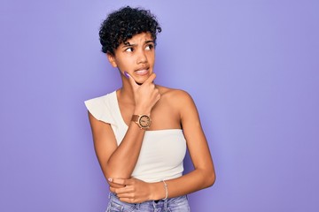 Young beautiful african american afro woman wearing casual t-shirt over purple background Thinking worried about a question, concerned and nervous with hand on chin