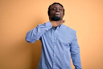 Fototapeta premium Young handsome african american man wearing shirt and glasses over yellow background cutting throat with hand as knife, threaten aggression with furious violence