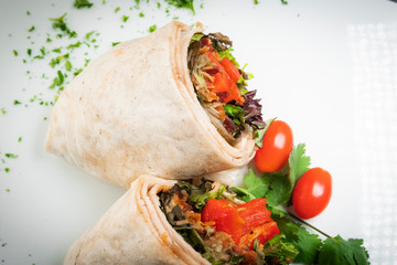 A fresh tasty California turkey wrap displayed on white platter with chopped parsley garnish