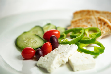 Shallow focus view of simple Greek meze food platter; with vegetables, pita, and feta