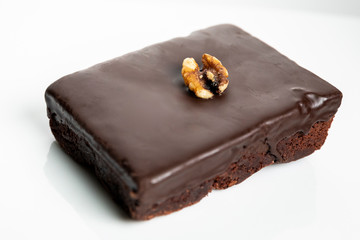 Shallow focus view of delicious chocolate fudge brownie and walnut garnish on top; on white platter