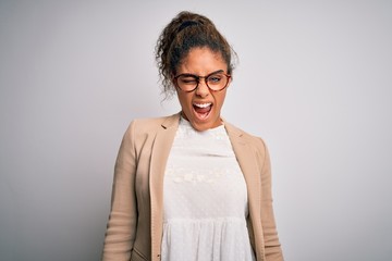 Beautiful african american businesswoman wearing jacket and glasses over white background winking...