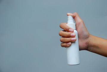 Hand of young Asian woman holding antibacterial spray bottle