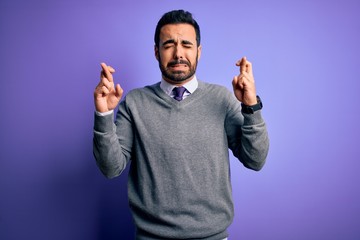 Fototapeta premium Handsome businessman with beard wearing casual tie standing over purple background gesturing finger crossed smiling with hope and eyes closed. Luck and superstitious concept.