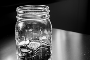 Glass tip jar partly full of loose coin change