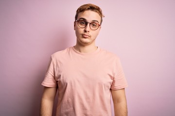 Young handsome redhead man wearing casual t-shirt standing over isolated pink background Relaxed with serious expression on face. Simple and natural looking at the camera.