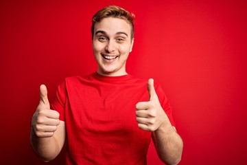 Young handsome redhead man wearing casual t-shirt over isolated red background success sign doing positive gesture with hand, thumbs up smiling and happy. Cheerful expression and winner gesture.