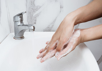 Young man washing hands over sink in bathroom, closeup, Corona virus or Covid-19 prevention,...