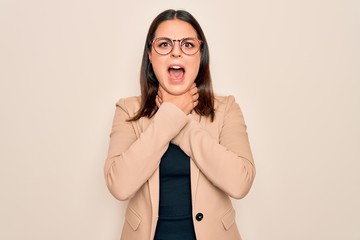 Young beautiful brunette businesswoman wearing jacket and glasses over white background shouting and suffocate because painful strangle. Health problem. Asphyxiate and suicide concept.