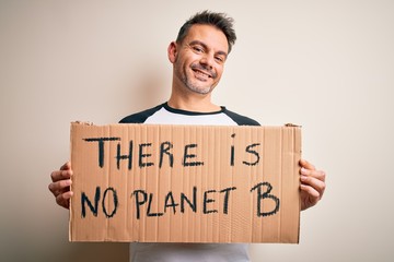 Young handsome man asking for environment holding banner with planet message with a happy face standing and smiling with a confident smile showing teeth