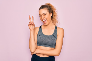 Young beautiful blonde sportswoman with blue eyes doing exercise wearing sportswear smiling with...