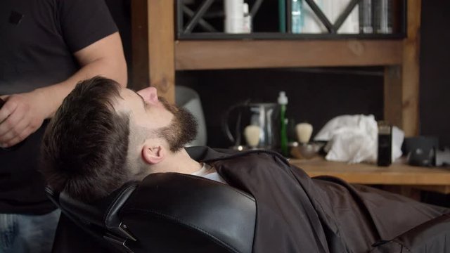 Barber spraying water on head of client
