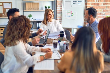 Group of business workers working together. Sitting on desk using laptop reading documents at the office