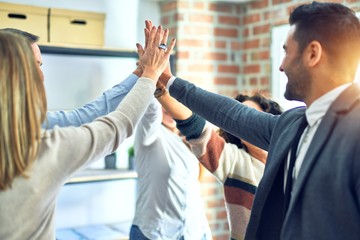 Group of business workers standing with hands together highing five at the office