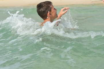 A happy caucasian child boy is swimming and having fun in the sea. Health spending time on summer holidays and hardening the body