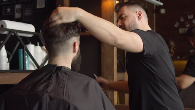 Barber cutting hair of male client