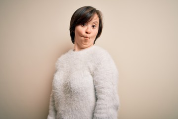 Young down syndrome woman standing over isolated background making fish face with lips, crazy and comical gesture. Funny expression.