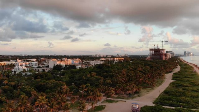 Pan right from aerial drone shot from Miami Beach township to calm sea at sunrise