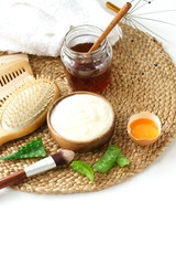 Homemade hair mask and ingredients for moisturizing honey, egg, yogurt, aloe on white background.