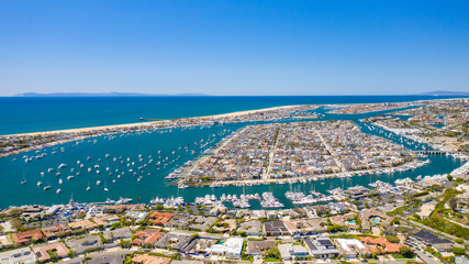 Aerial view of coastal homes in Newport Beach harbor, Orange County, California on a sunny day with boats in the water with Balboa Island.