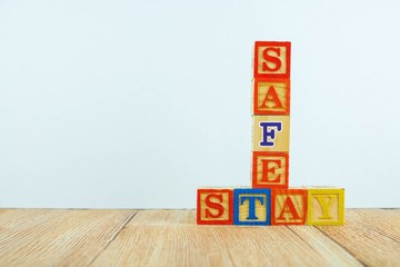 Wooden alphabet cubes over wooden texture. Conceptual of stay safe during virus outbreak lock down, crisis or emergency. Focus on selective cubes. Others in gradient blur.