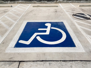 International handicapped (wheelchair) or Disabled parking symbol painted in bright blue on parking space.