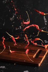 Falling dried red hot chili with sichuan pepper seasoning mala powder on wood board isolated...