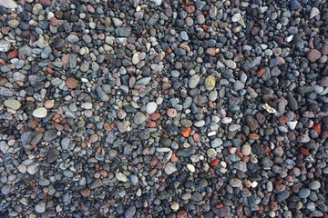 Colorful pebble beach natural horizontal background with tumbled volcanic stones and coral