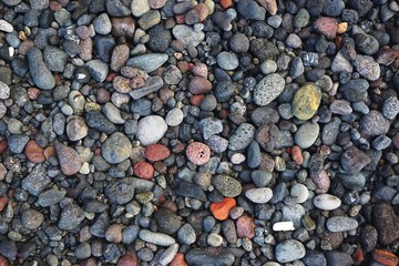 Closeup detail of coarse irregular colorful tumbled beach pebbles