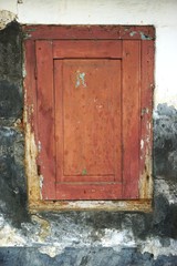Funky weathered brown wooden door set in ancient dirty stucco wall vertical background
