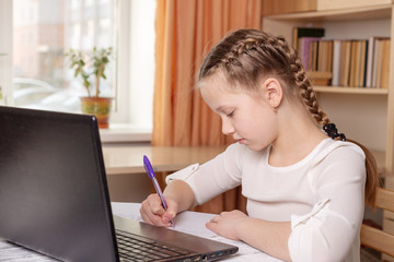 Schoolgirl does homework. Social distance, self-isolation. Home school, online education, home education, quarantine concept