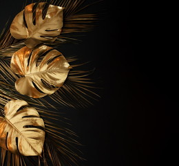 Gold leaves frame isolated on black background. Palm and monstera leaves top view.Copy space