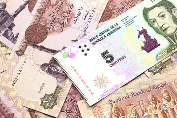 A five peso bank note from Argentina on a background of Egyptian one pound bank notes close up