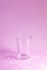 empty glass and water drop on pastel background