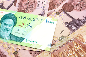 A macro image of a green ten thousand rial bank note from Iran on a bed of Egyptian one pound bank notes close up