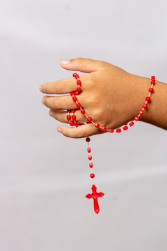 Hand Of A Child With A Red Rosary In Hand.