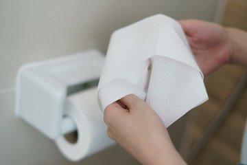 Hand pulling a roll of toilet paper tissue.