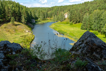 natural landscape of a river running through the forest in the foreground cliffs in the shade