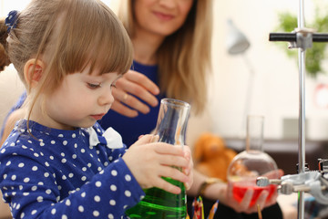 Woman and little girl play with colourful liquids portrait. Young team clean research equipment colour reagent food additions flavor activity mother flavour concept