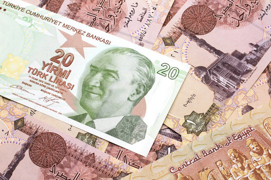 A close up image of a green twenty Turkish lira bank note on a background of Egyptian one pound bank notes in macro