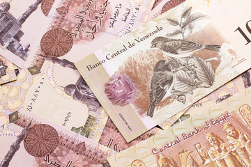 A Venezuelan one hundred Bolivares bank note, close up in macro on a bed of Egyptian one pound bank notes