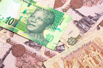 A close up image of a green ten rand bank note from South Africa in macro on a bed of Egyptian one pound bank notes