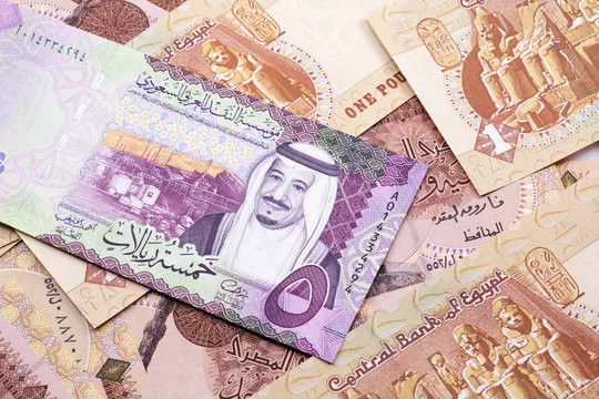 A close up image of a five riyal bank note from Saudi Arabia on a background of Egyptian one pound bank notes in macro