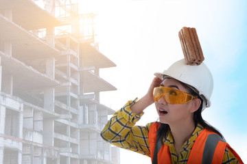 The stick block brick fell on the Asia engineer young woman head on the helmet worker at white background, Area construction safety first concept