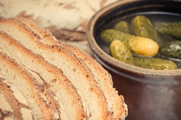Vintage photo, Slices of fresh baked rye or wheat bread and pickled cucumbers in clay pot