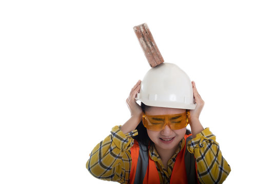 The stick block brick fell on the Asia engineer young woman head on the helmet worker at white background, Area construction safety first concept