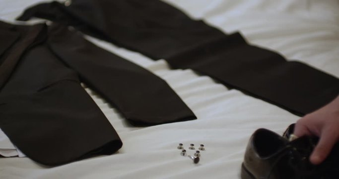 Black man picks up shoes from bed